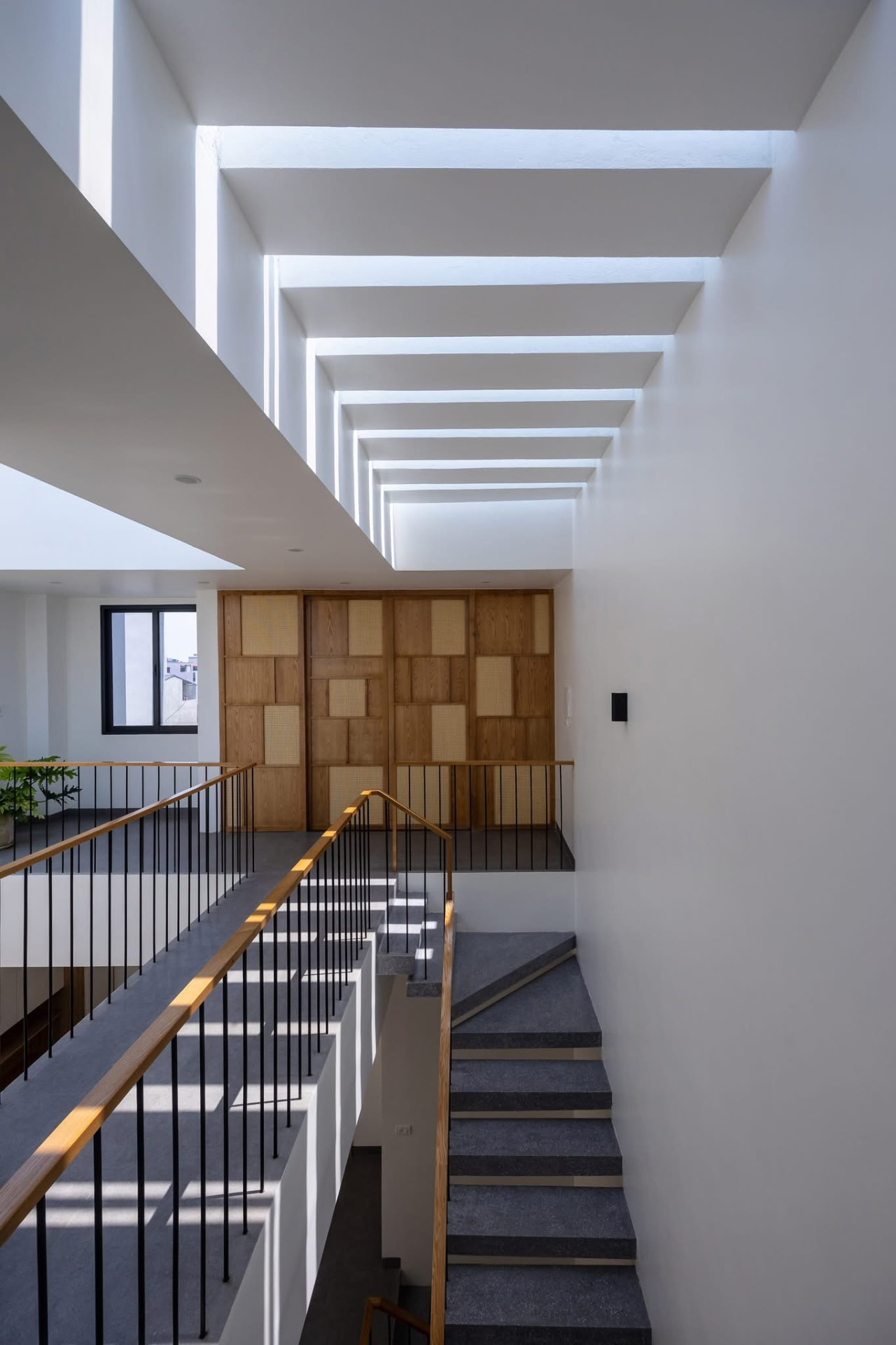 Double-height stair void with cane and oak screen wall