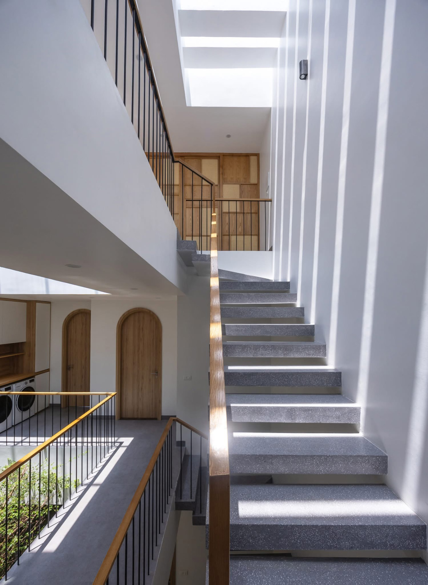 Terrazzo stair with brass nosings rising past the screen wall