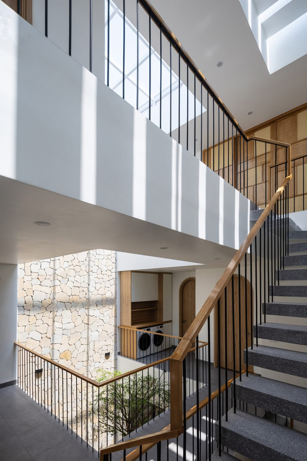 Skylit stair void with oak handrail and cane screen