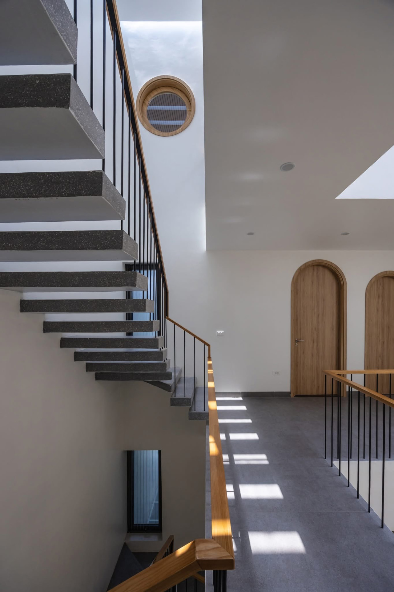 Floating stone treads beside a round timber-framed window