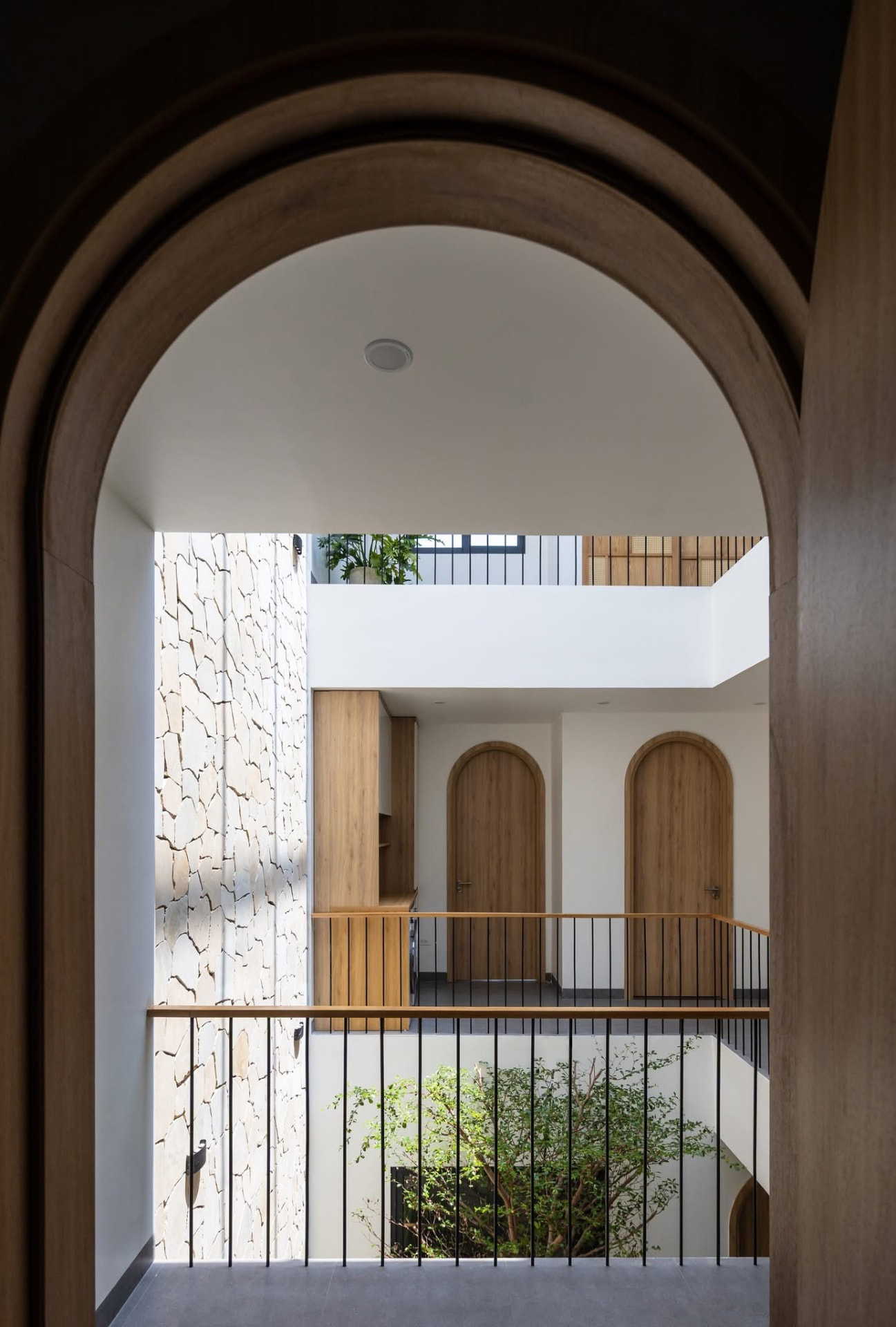 Landing seen through a timber arch, stone wall and courtyard beyond