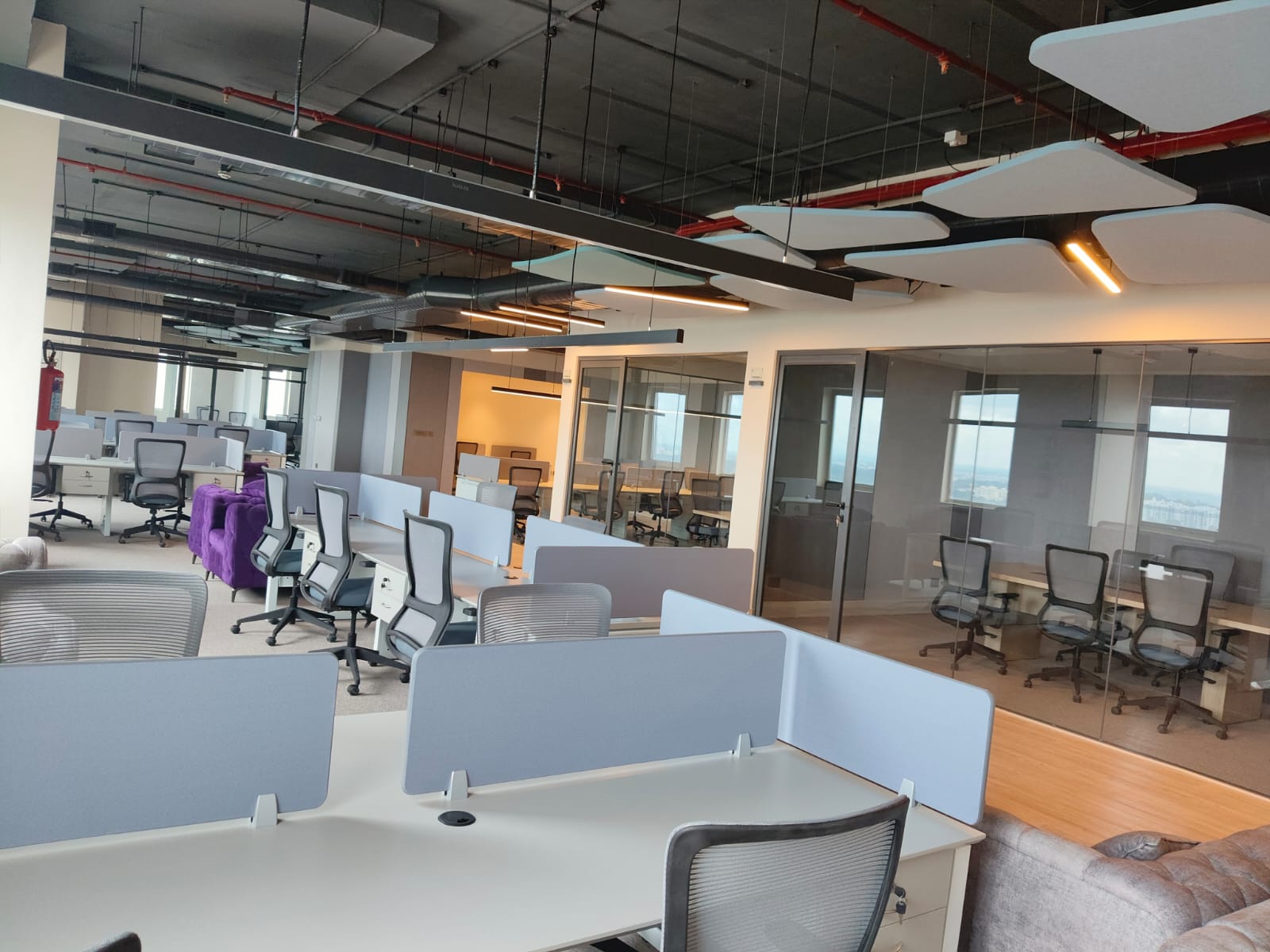 Desk clusters and meeting rooms under exposed services and linear lighting