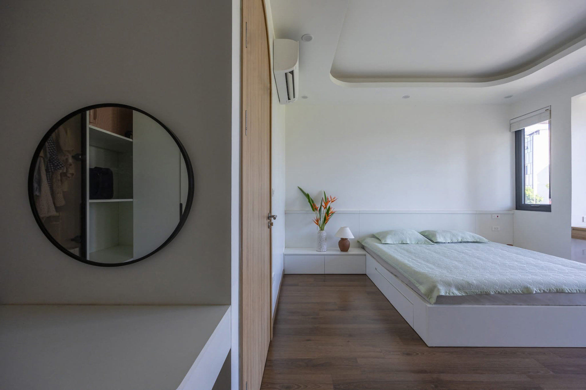 Bedroom with round wardrobe mirror and platform bed