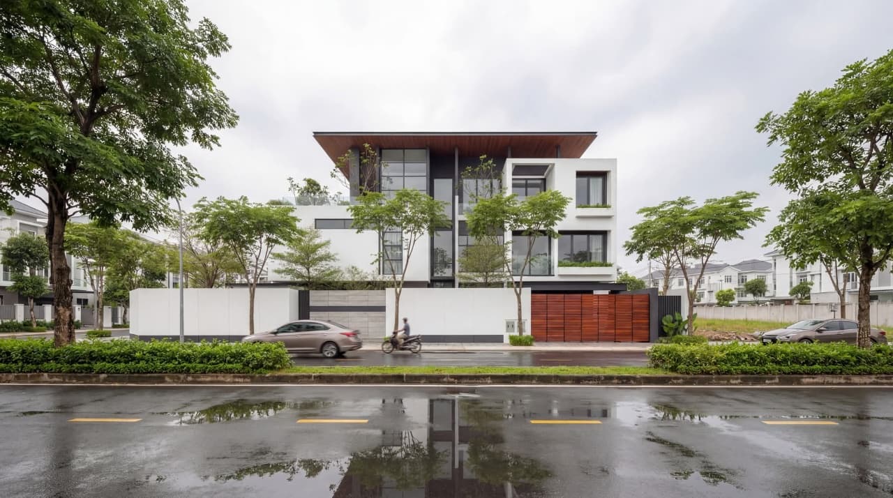 Wide street view of the residence with layered tree canopy