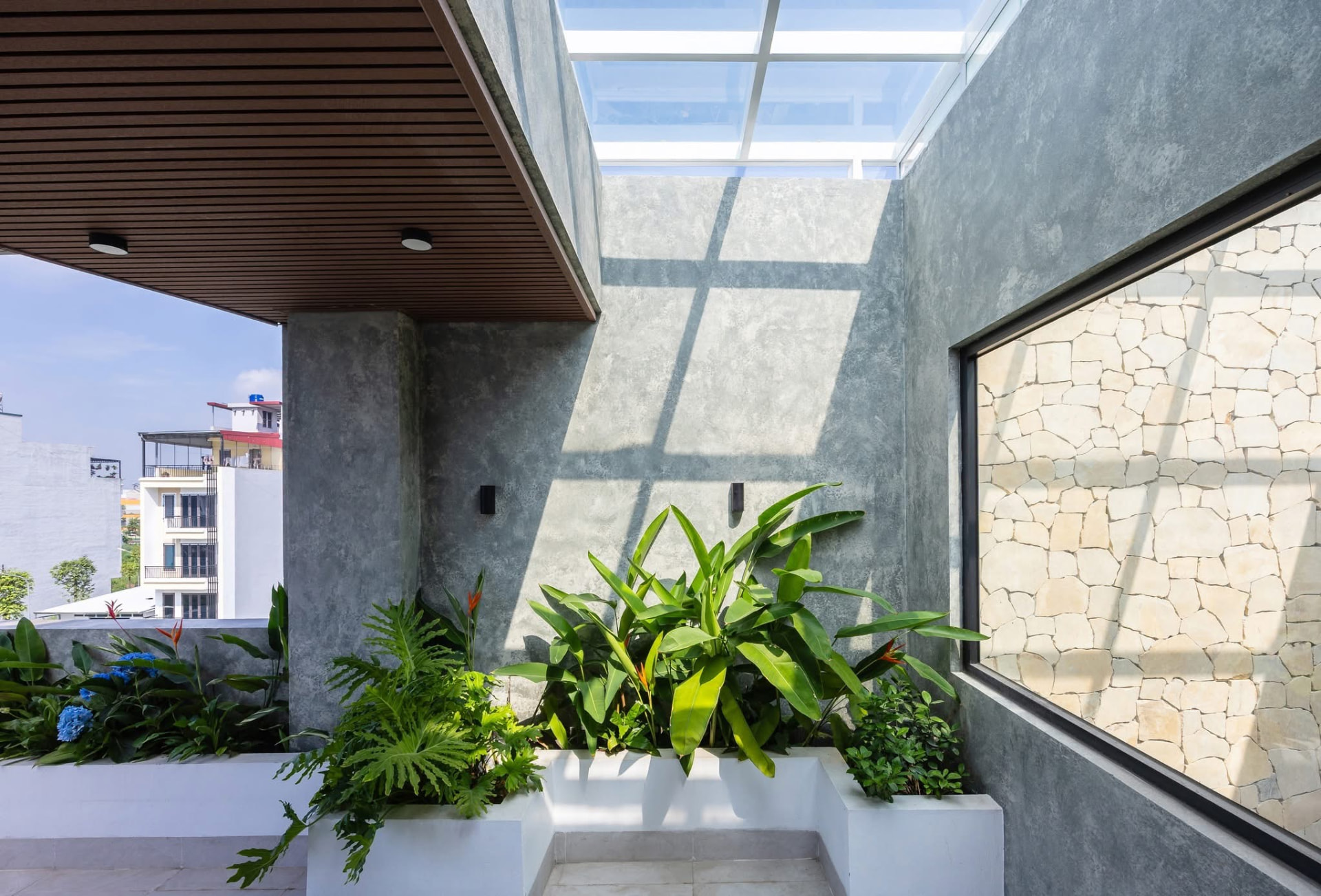 Terrace court under a glazed roof with planters and lime-washed walls