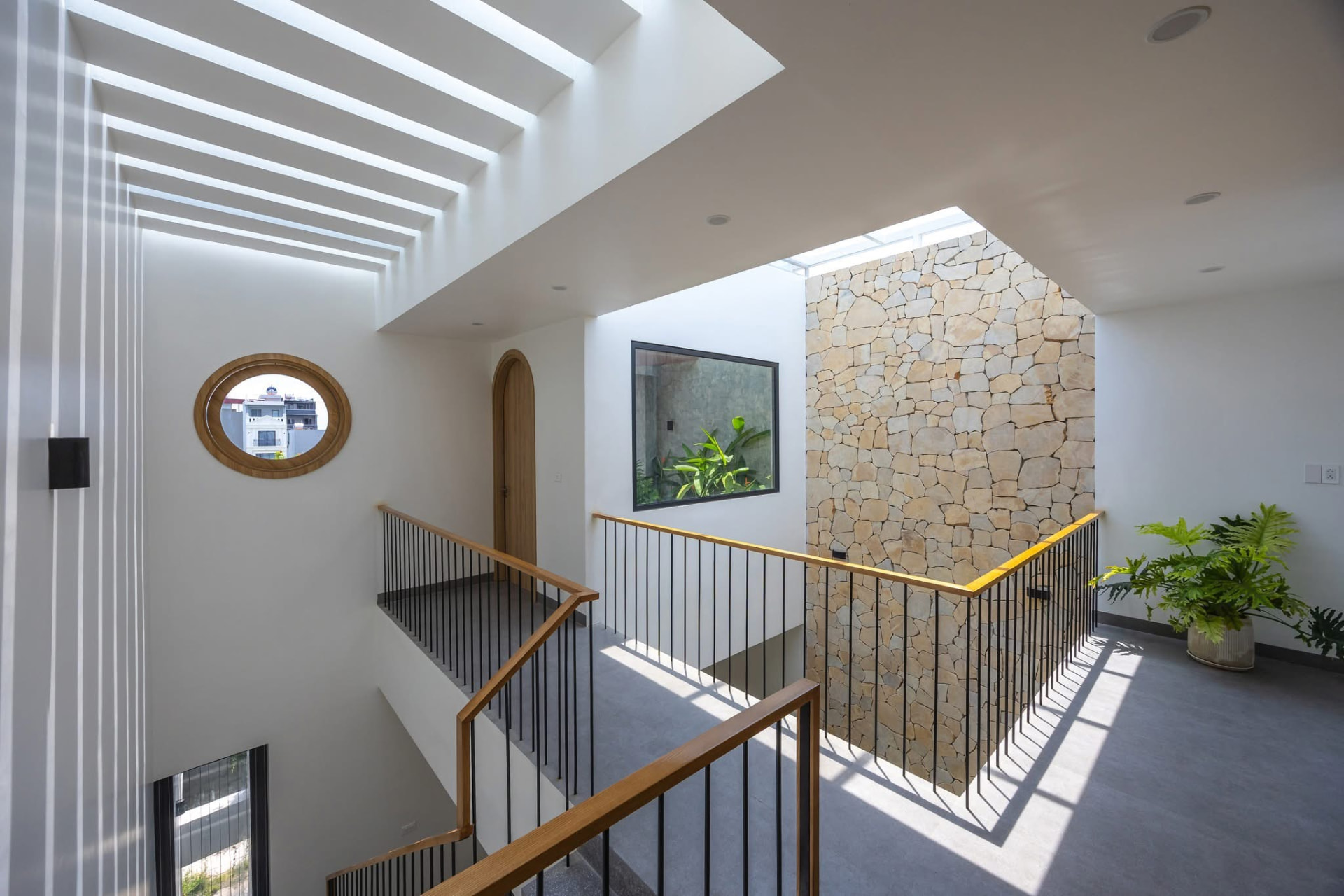 Stair hall with rubble stone core, oval window and skylit slot ceiling