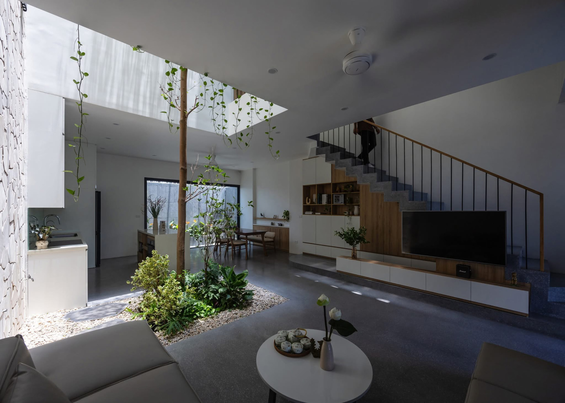 Living and dining volume with the stone stair rising behind